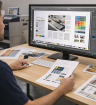 A professional pre press technician reviewing print-ready files on a large monitor